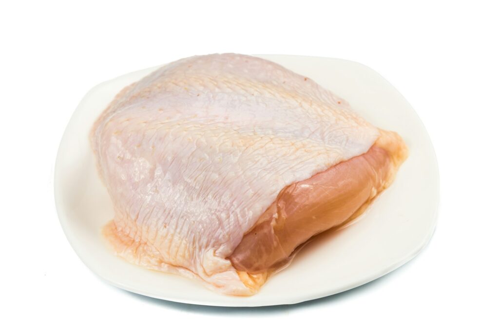 Fresh chicken breast meat with skin on plate