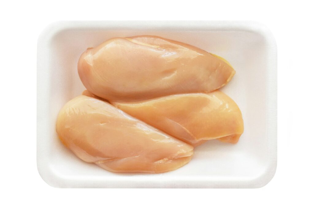 Raw chicken breast fillet on a food tray.